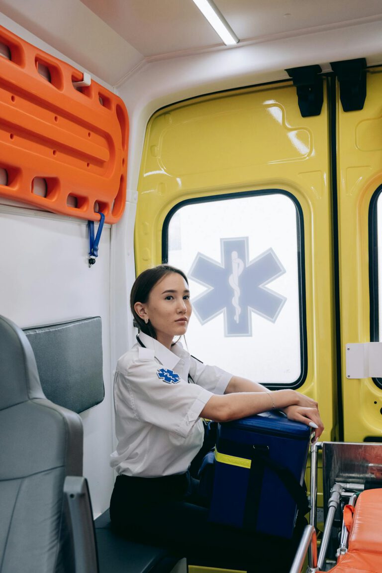 Asian female paramedic sitting inside an ambulance, ready for emergency response.