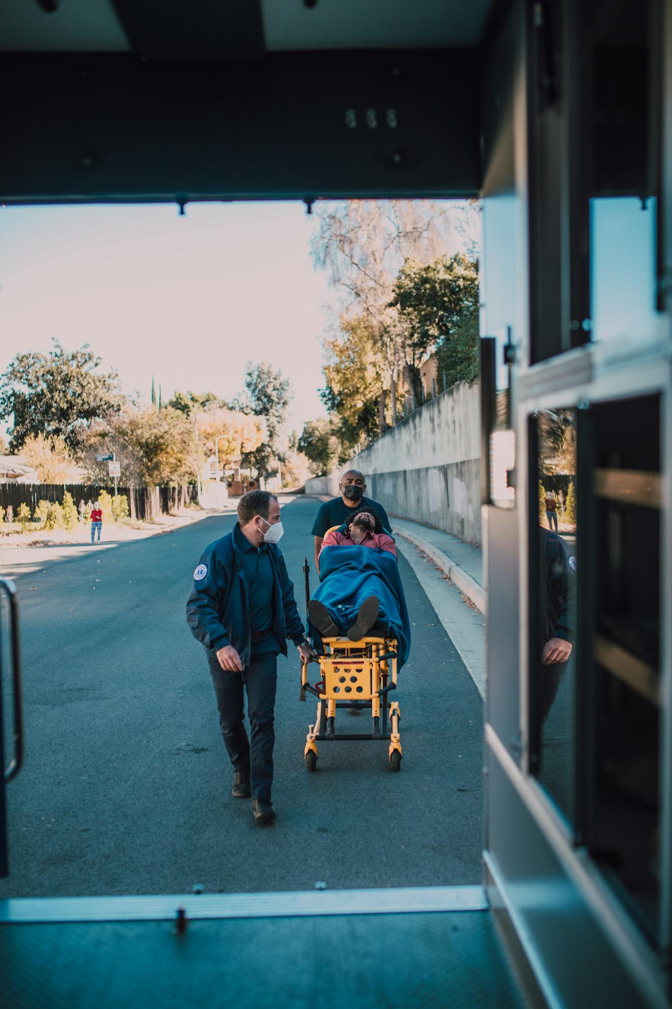 Paramedics assist a patient on a stretcher by the roadside, showcasing urgent medical care.