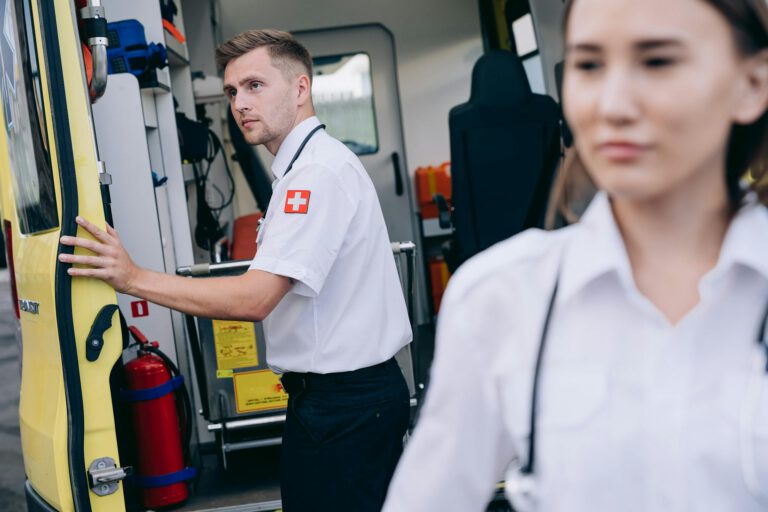 Two paramedics in uniform prepare an ambulance for emergency response, emphasizing teamwork and readiness.
